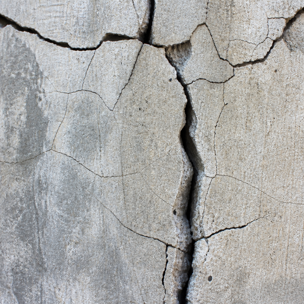 Photographie rapprochée montrant différents types de fissures dans le béton avec variations de largeur et de motifs
