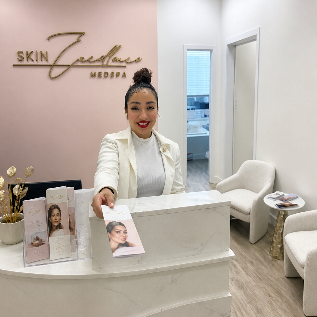 Receptionist welcoming a client at a bright medspa reception area.